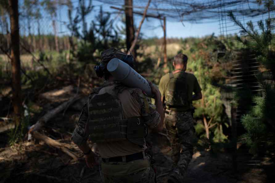 A Ukrainian soldier carries a shell towards a howitzer on the front...