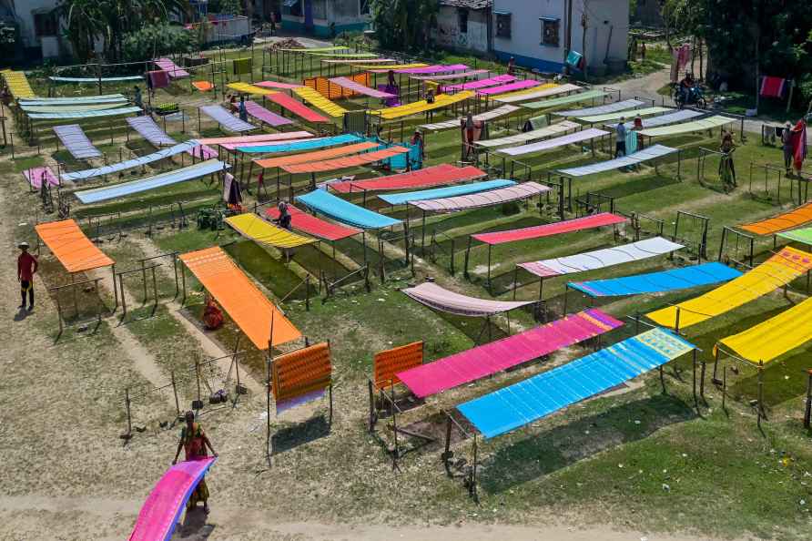 Workers dry handloom clothes