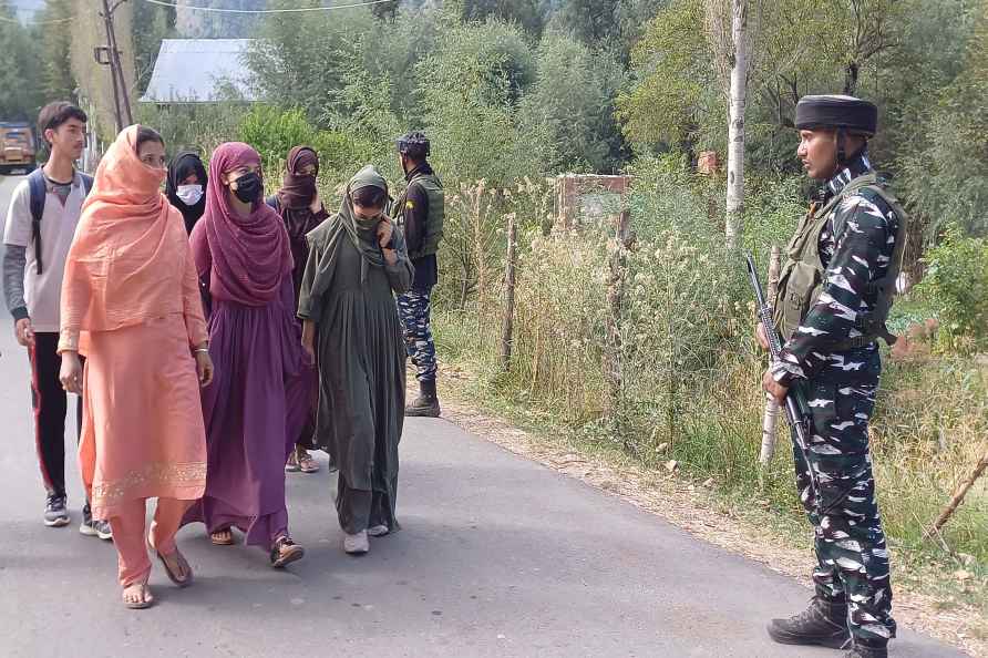 Anantnag: Security personnel stand guard as students walk to their...