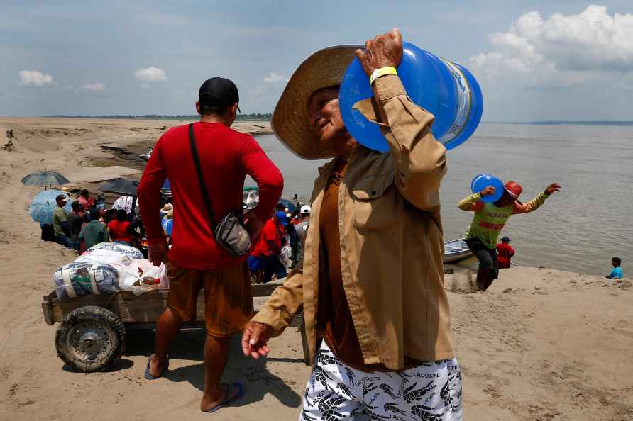 A resident of a riverside community carries a container of drinking...