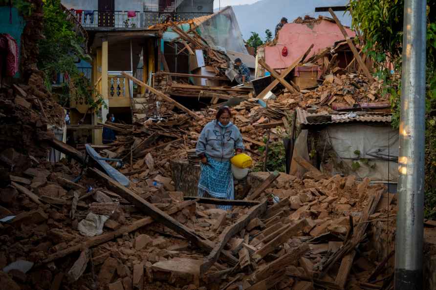 A woman walks past earthquake damaged houses in Jajarkot district...