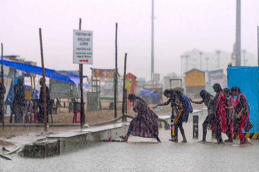 Tuticorin: Commuters amid rains on a waterlogged road, near Marina...