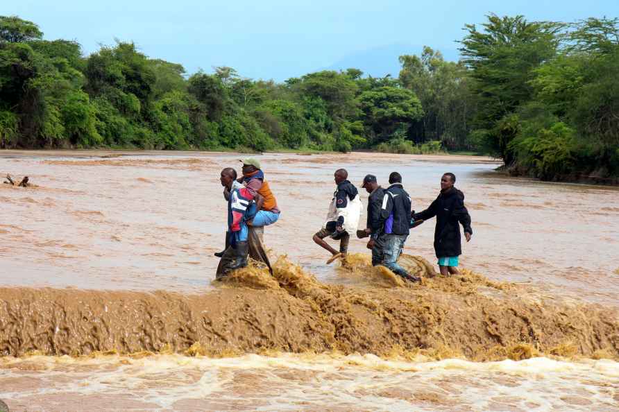 People are helped to cross through a flooded Muuoni River