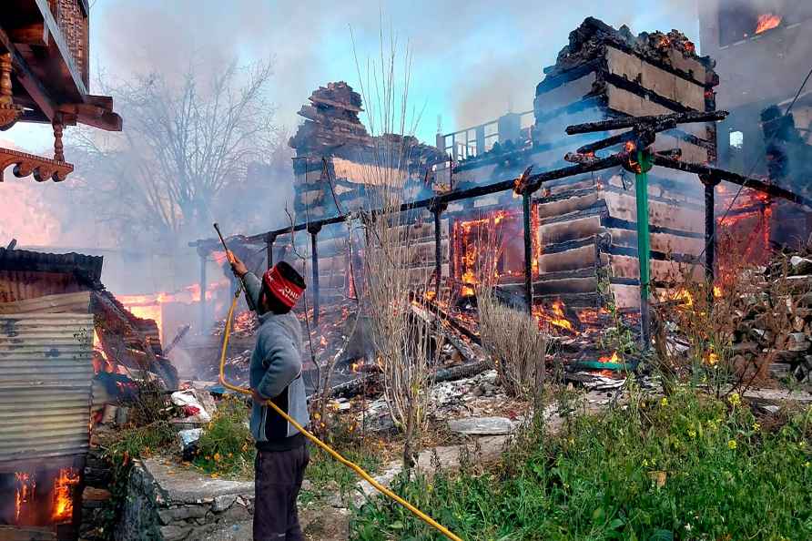 Kullu: A man tries to douse a fire at Pathila village of Sainj Valley...