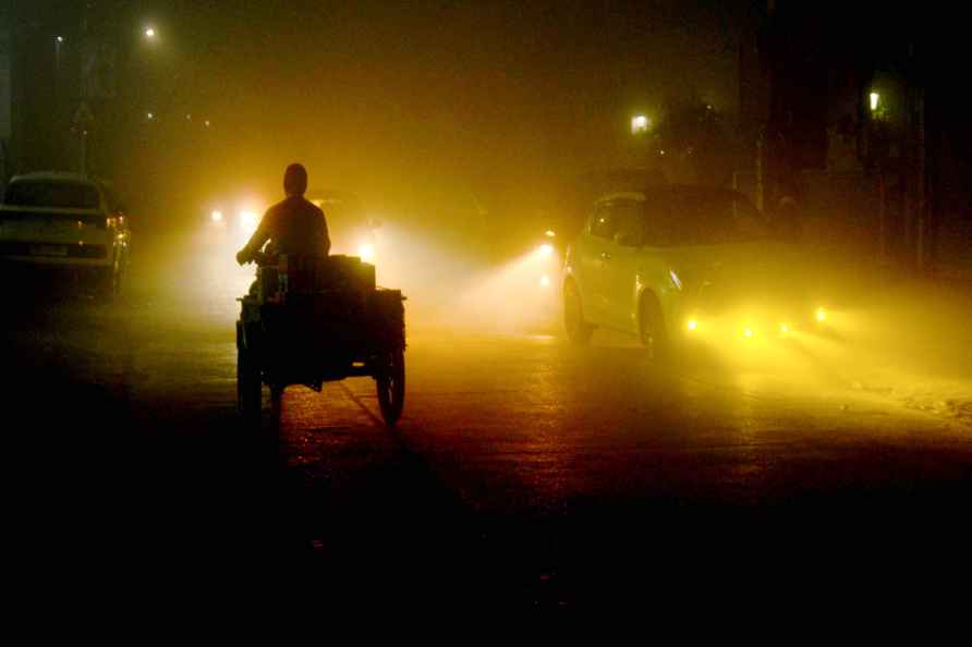 Patiala: Vehicles on a road amid fog on a winter evening, in Patiala...