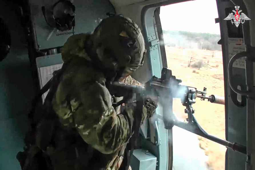 A Russian soldier fires from aboard of a Mi-8 search