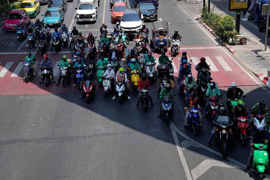 Motorcyclists stop in the shade of a skytrain line on a hot day ...