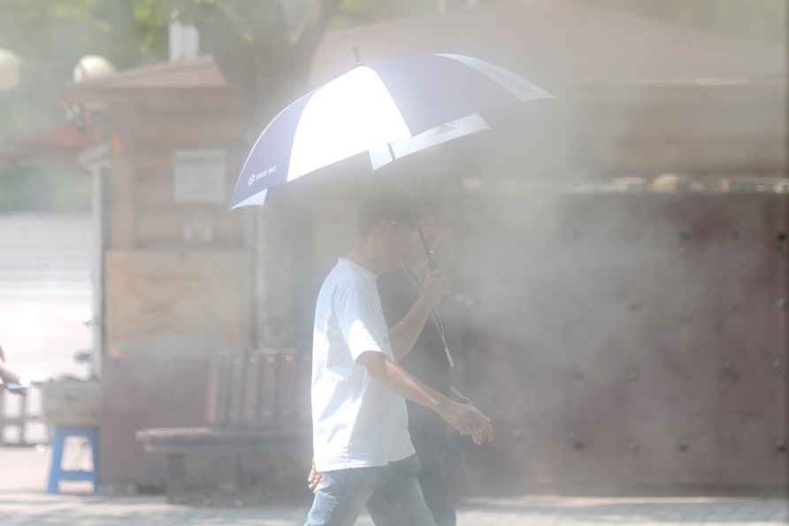 People, carrying an umbrella to protect themselves from the heat...