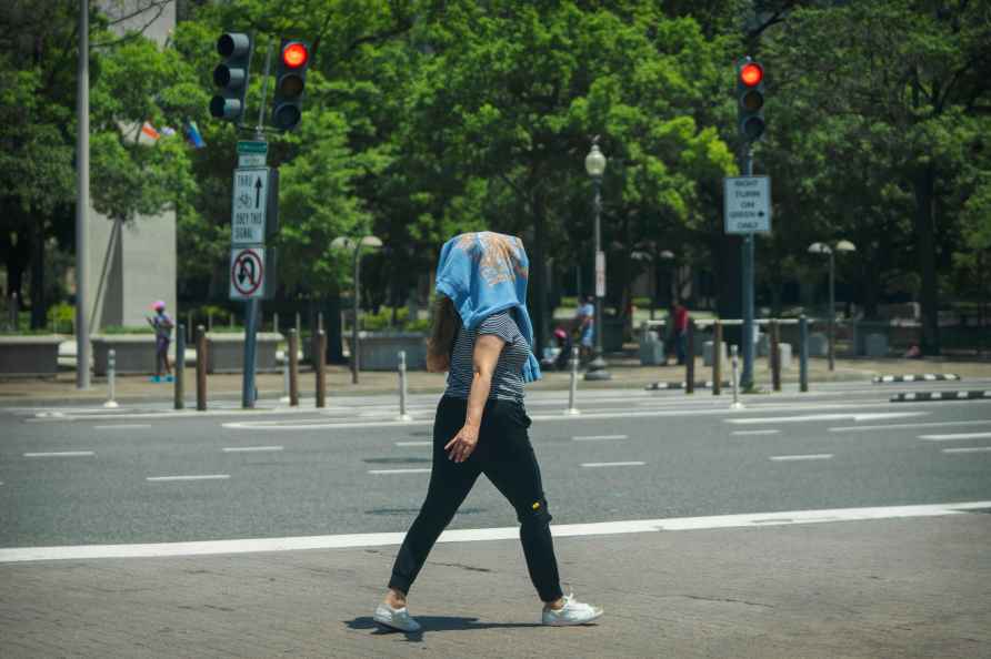 A woman wearing a sweatshirt on her head to protect herself from the sun