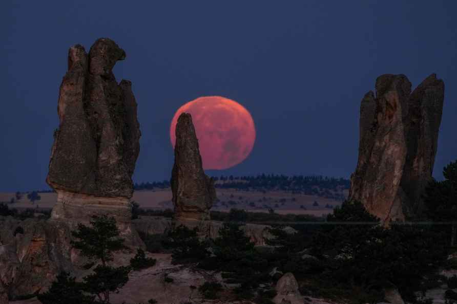 A supermoon sets behind rocks