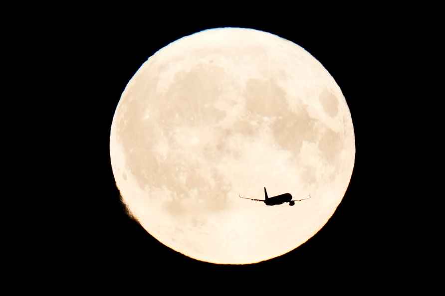 A plane passes by the supermoon over Copenhagen, Monday, Aug. 19...