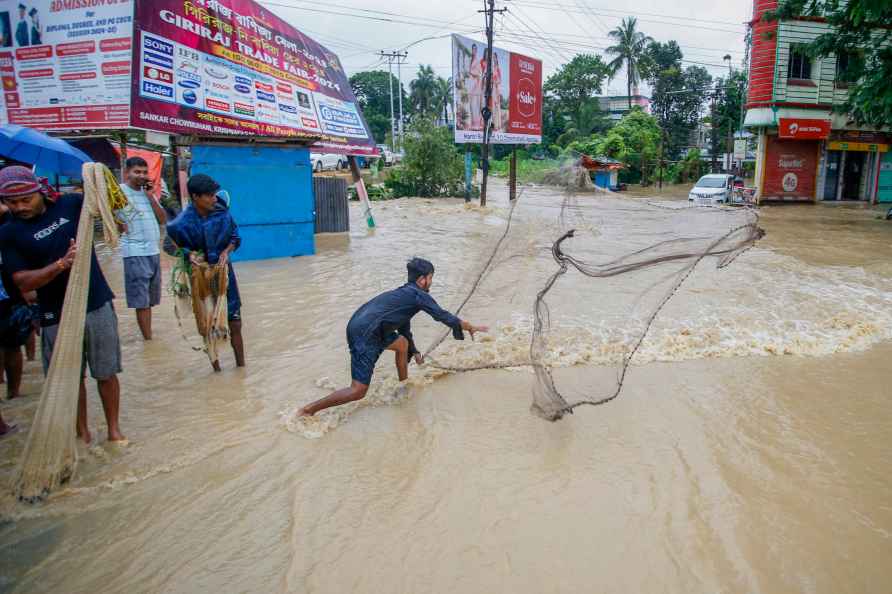 Agartala: A man casts a net to catch fish on a flooded road following...